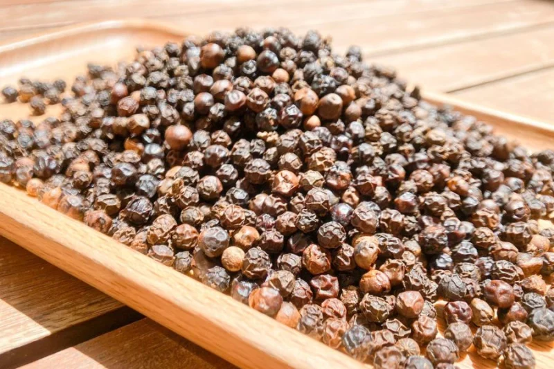 Hạt tiêu đen chất lượng cao được đặt trên khay gỗ tự nhiên