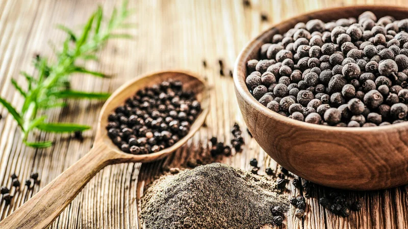 Hình ảnh hạt tiêu đen nguyên hạt và bột tiêu trên bàn gỗ